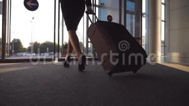 商务女士带着行李通过自动玻璃门离开机场。 从终点站走出来的年轻女子